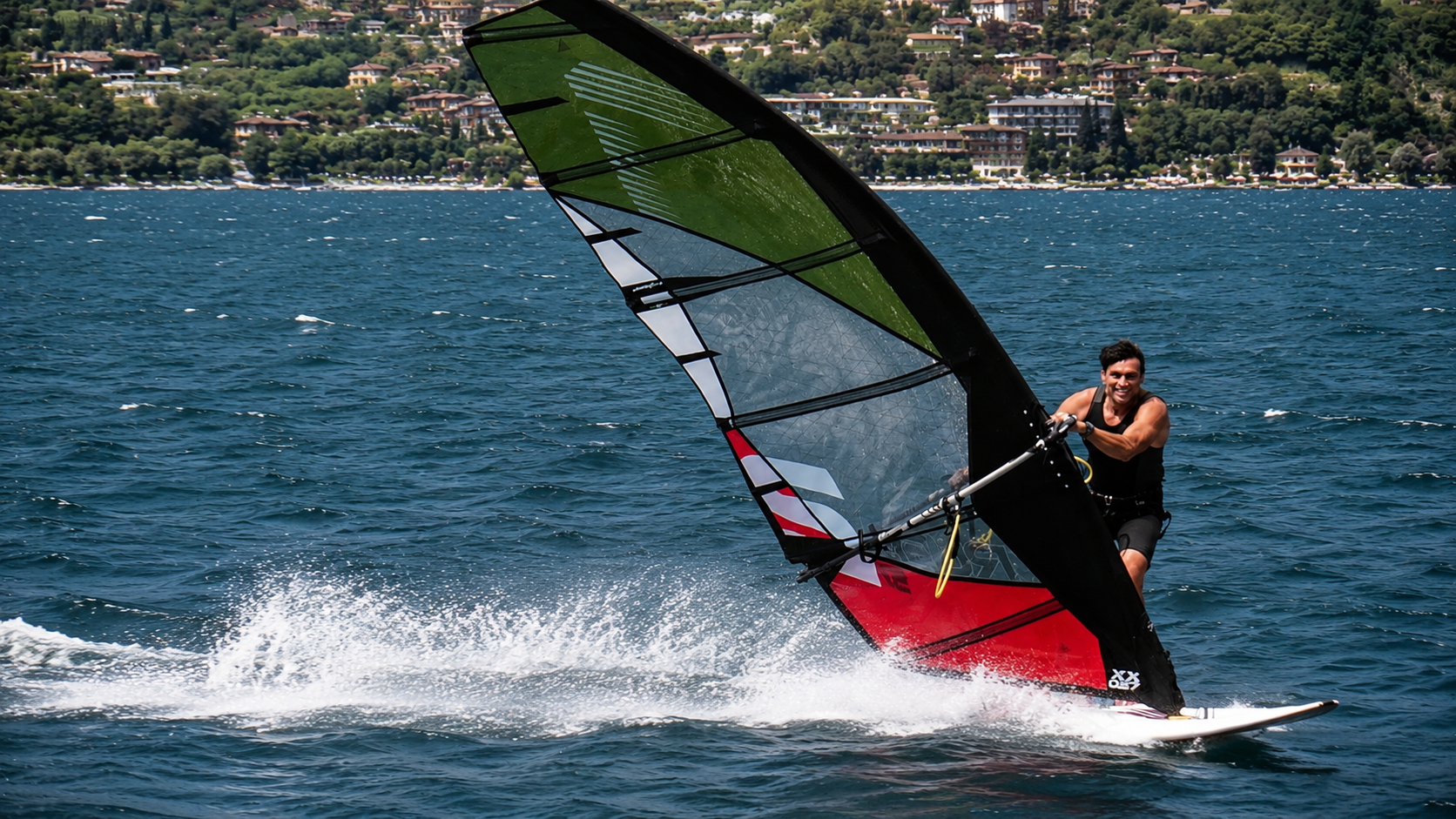 Windsurfer blasting across the water with a green, white and red Point-7 sail.
